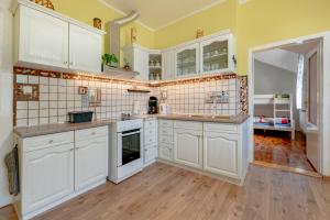 a large kitchen with white cabinets and wooden floors at art-house 1 apartment with terrace in Děčín