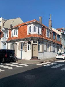 una casa blanca con techo naranja en una calle de la ciudad en Chrysalide au cœur du Touquet., en Le Touquet-Paris-Plage