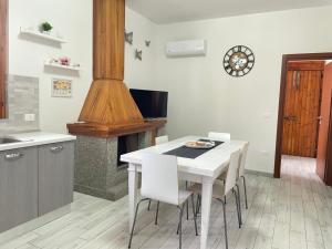 uma cozinha com uma mesa e cadeiras brancas e um fogão em Villa Berenice em Pachino