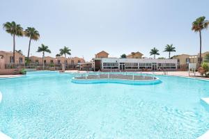 a large swimming pool in a resort with palm trees at Sweet Holidays in Maspalomas