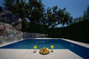 een fruitschaal en twee glazen sinaasappelsap naast een zwembad bij Villa Asmaaltı in Demre