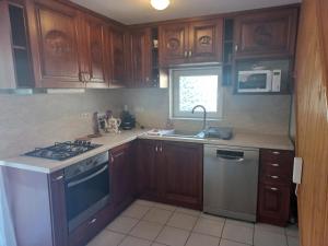 a kitchen with wooden cabinets and a stove and a sink at Krisztina Apartman 1- Szigethalom in Szigethalom
