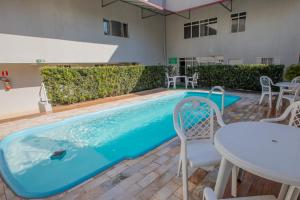 a pool with a table and chairs next to a building at A1 hotel in Foz do Iguaçu
