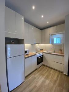 una cucina con armadietti bianchi e frigorifero bianco di Sea Through Apartment Anavissos ad Anávissos