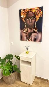 a picture of a black woman on a wall with a table at Sea Through Apartment Anavissos in Anavissos