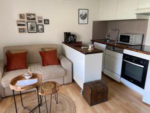 een woonkamer met een bank en een keuken bij Appartement TETHYS in Sète