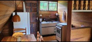 a small kitchen with a refrigerator and a table at Sitio Vale Piemonte "Chalés " in Santo Antônio do Pinhal