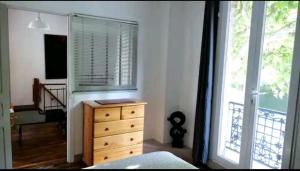 ein Schlafzimmer mit einer Holzkommode und einem Fenster in der Unterkunft Comme une petite maison en ville in Montrouge