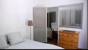 ein Schlafzimmer mit einem Bett, einer Kommode und einem Fenster in der Unterkunft Comme une petite maison en ville in Montrouge