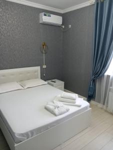 uma cama branca com toalhas num quarto em Keruen Deluxe em Taraz
