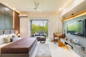 Schlafzimmer mit einem Bett und einem Flachbild-TV in der Unterkunft The Magnolia Farm by StayVista - Indoor Pool Villa with Jacuzzi & Terrace in Amritsar
