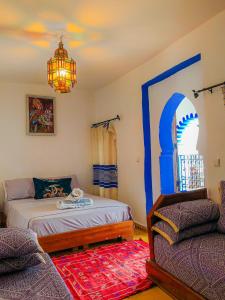 a bedroom with a bed and a couch and a chandelier at Riad Said Chaouen in Chefchaouene