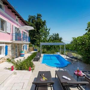 a swimming pool with tables and chairs next to a house at NINA ROSE boutique villa in Lovran