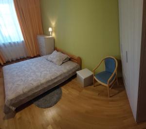 a small bedroom with a bed and a chair at Holiday Apartment in Liepāja