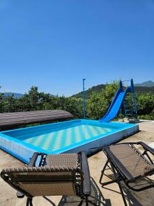 a swimming pool with two chairs and a slide at Idiličan brijeg in Višegrad