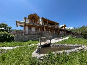 a house on a hill with a pond in front of it at Forest INN in Antaramej