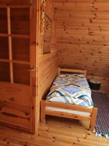 a small bed in a room with wooden walls at Domek nad jeziorem in Suwałki