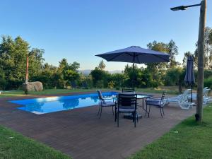 a table with chairs and an umbrella next to a pool at Quinta da Meda in Coimbra