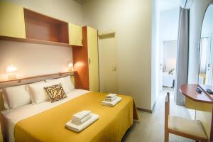 Una habitación de hotel con una cama amarilla con toallas. en B&B Hotel Serenità, en Bellaria-Igea Marina