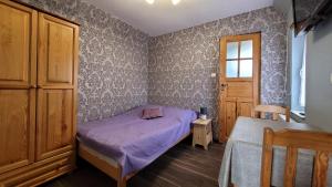 um pequeno quarto com uma cama roxa e uma janela em Pańska Izba em Chałupy