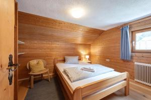 ein kleines Zimmer mit einem Bett in einer Holzwand in der Unterkunft Chalet Stanzertal in Strengen