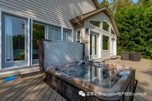 a hot tub on a deck in front of a house at luxury ocean dock pool villa in Ladysmith