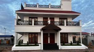 a white house with a balcony on top of it at GRB RESORT in Tiruchchendūr