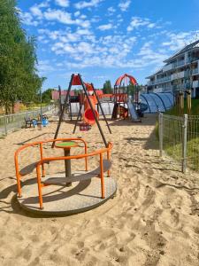 a playground with an orange swing set in the sand at Apartament z basenem Baltic Garden Sztutowo, Mierzeja Wiślana in Sztutowo