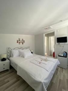 a bedroom with a large white bed and a flat screen tv at Heybeliada Pansiyon in Istanbul