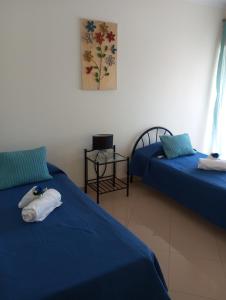 um quarto com duas camas com lençóis azuis em T-3 Frente Mar lote19- Casas & Papeis em Armação de Pêra