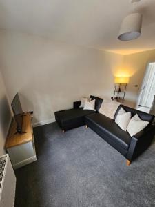 a living room with a black couch and a television at Oakmere Apartments in Chinley