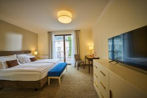 1 dormitorio con 1 cama y TV de pantalla plana en Wellness Hotel Queens en Mariánské Lázně