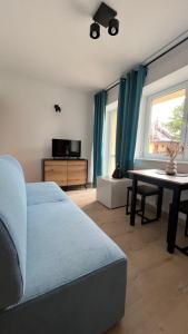 uma sala de estar com um sofá azul e uma mesa em Kraken-pokoje gościnne em Krynica Morska