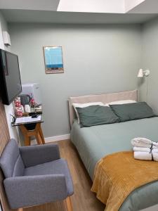 布萊頓霍夫的住宿－Central ensuite guest unit with free on-street parking，一间卧室配有一张床、一把椅子和电视。