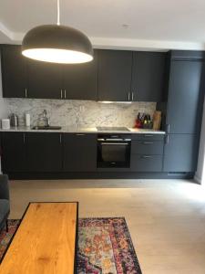 a kitchen with black cabinets and a wooden table at Bjørvika/sjøsiden ved Barcode in Oslo