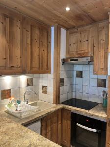 a kitchen with wooden cabinets and a sink at Tignes le Lac - Appartement au pied des pistes in Tignes