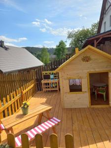 a wooden deck with a picnic table and a play house at Prázdninový dům Sloup - Sloup v Čechách in Sloup
