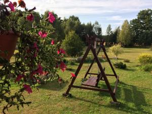 a wooden swing in the grass next to flowers at Gościniec Pod Dębami in Puchły +14 photos