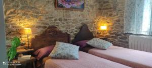 a bedroom with two beds and a stone wall at WITERICUS hospedaxe in Guitiriz +12 photos