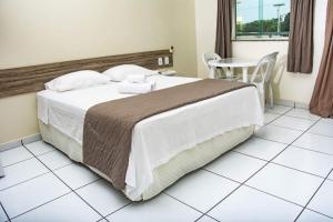 1 dormitorio con 1 cama grande y 1 mesa en Pousada Aeroporto en Parnaíba