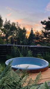 una bañera de hidromasaje en un patio con una puesta de sol en el fondo en Domek Mały Las en Rzyki