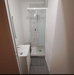 a white bathroom with a shower and a sink at Bel appartement avec Terasse Proche Gare in Cergy