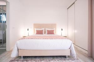 1 dormitorio blanco con 1 cama grande con almohadas rosas en Villa Serra Mar en São Martinho do Porto