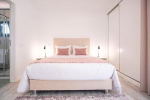 a white bedroom with a large bed with pink pillows at Villa Serra Mar in São Martinho do Porto