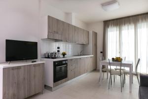 Residenza Riva Azzurra في ريميني: مطبخ بدولاب خشبي وطاولة مع تلفزيون