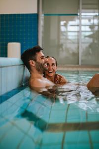 a man and woman in a swimming pool at Wiesenglück Tiny House Hotel in Heilbad Heiligenstadt