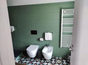 a green bathroom with a toilet and a sink at Hotel & Apartments " Perpoin " in Saluzzo