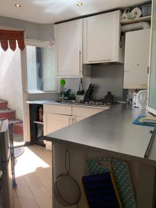 a kitchen with white cabinets and a counter top at Studio Apartment - Entire Lower Ground Floor - Only 7 Mins Walk Kings Cross St Pancras Station in London