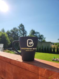 a coffee cup sitting on top of a wooden rail at Bursztynowe Wczasy Sasino in Sasino