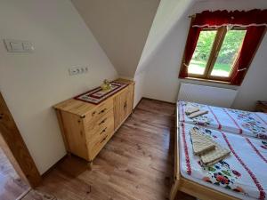 a bedroom with a bed and a dresser and a window at Chata na Zbojskej in Pohronská Polhora